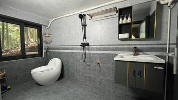 A modern bathroom with a toilet, shower, and sink.