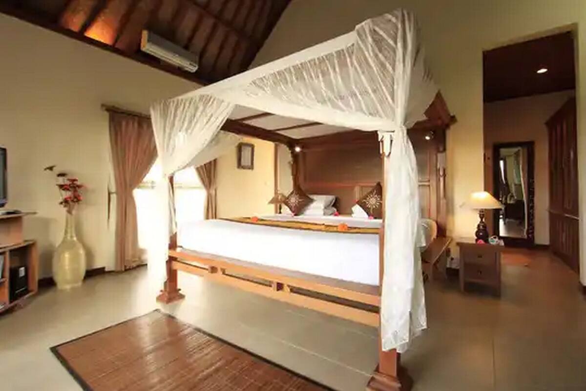 A four-poster bed with a canopy, a wooden headboard, and a bedside table with a lamp.