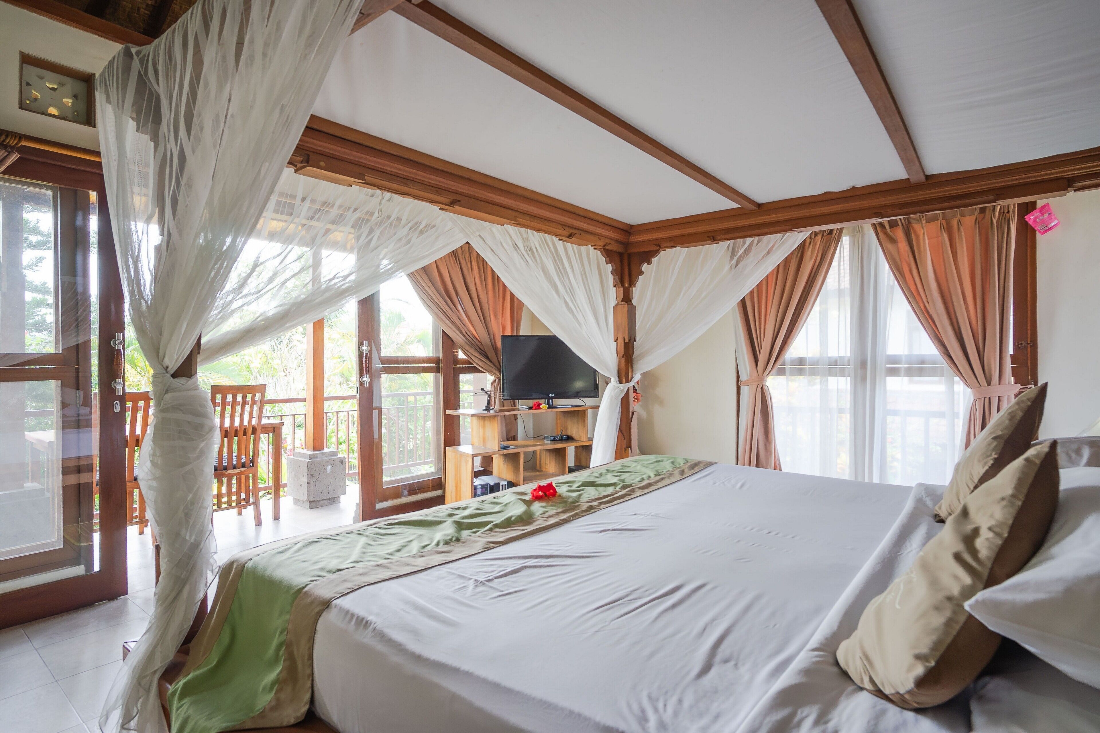 A bedroom with a bed, curtains, a television, and a balcony.