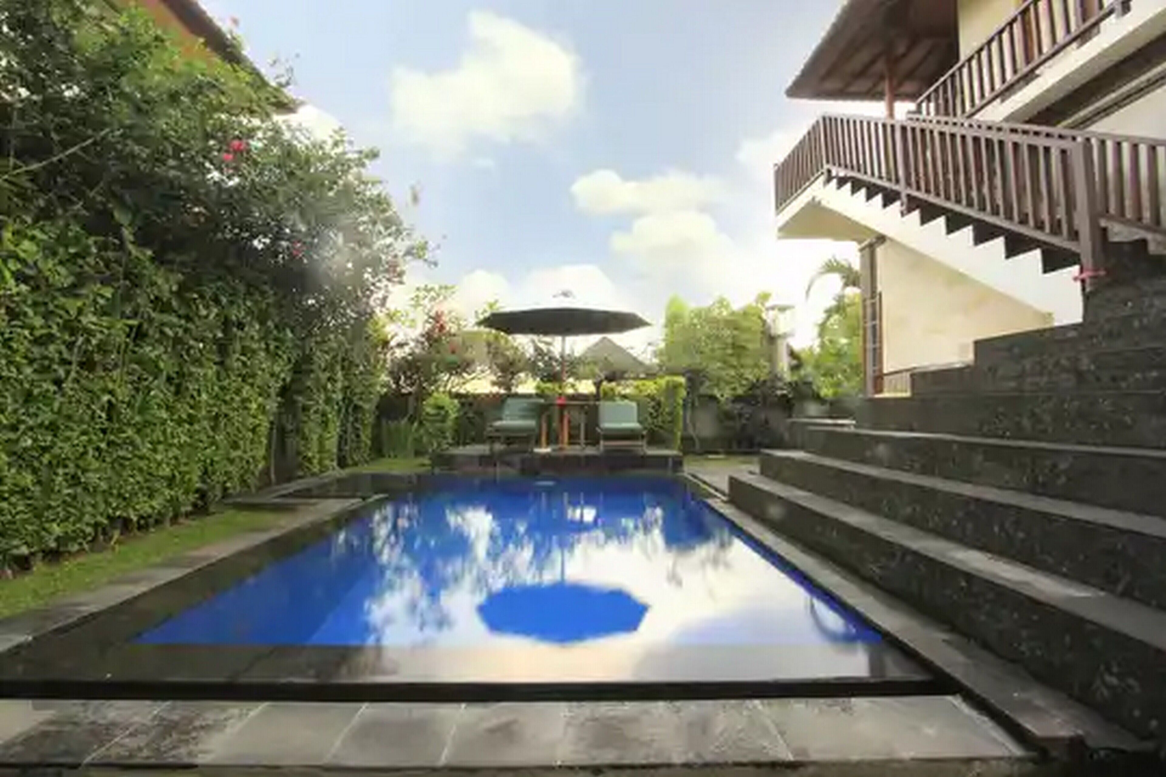 A rectangular swimming pool with a clear blue water surface, surrounded by stone steps and greenery.