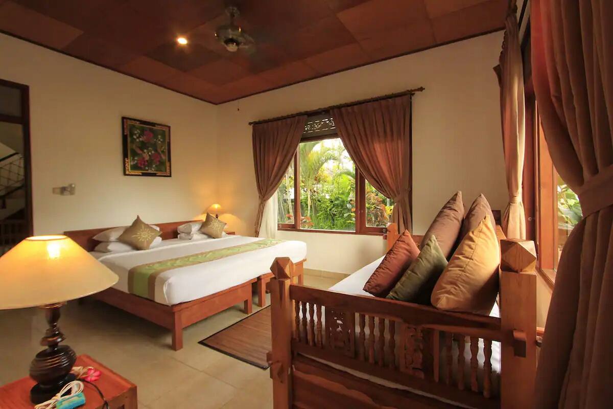 A hotel room with a bed, bedside table, lamp, and window with curtains.
