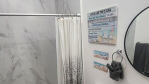 Un baño con ducha, inodoro, lavabo y espejo.