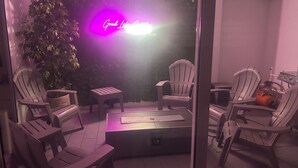 Un patio con varias sillas tipo Adirondack, una mesita y un letrero de neón.