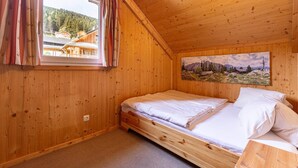A wooden cabin room with a bed, a window with curtains, and a painting on the wall. - Majestic chalet with terrace (Stadl an der mur)