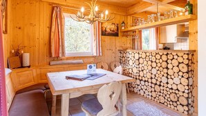 A wooden cabin interior with a dining table, bench seating, a chandelier, a fireplace, and a log wall. - Majestic chalet with terrace (Stadl an der mur)