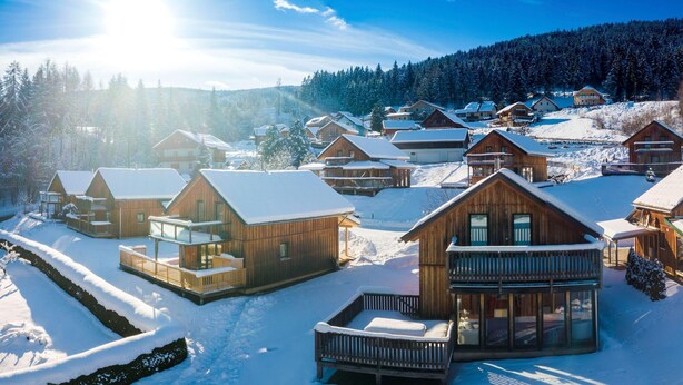 A snow-covered lodge with multiple wooden cabins, each featuring balconies and large windows. - Majestic chalet with terrace (Stadl an der mur)