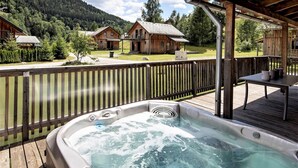 A hot tub on a wooden deck with a view of cabins and mountains. - Attractive chalet with sauna (Stadl an der mur)