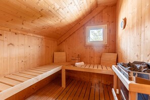 A wooden sauna with benches, a small window, and a heater. - Attractive chalet with sauna (Stadl an der mur)