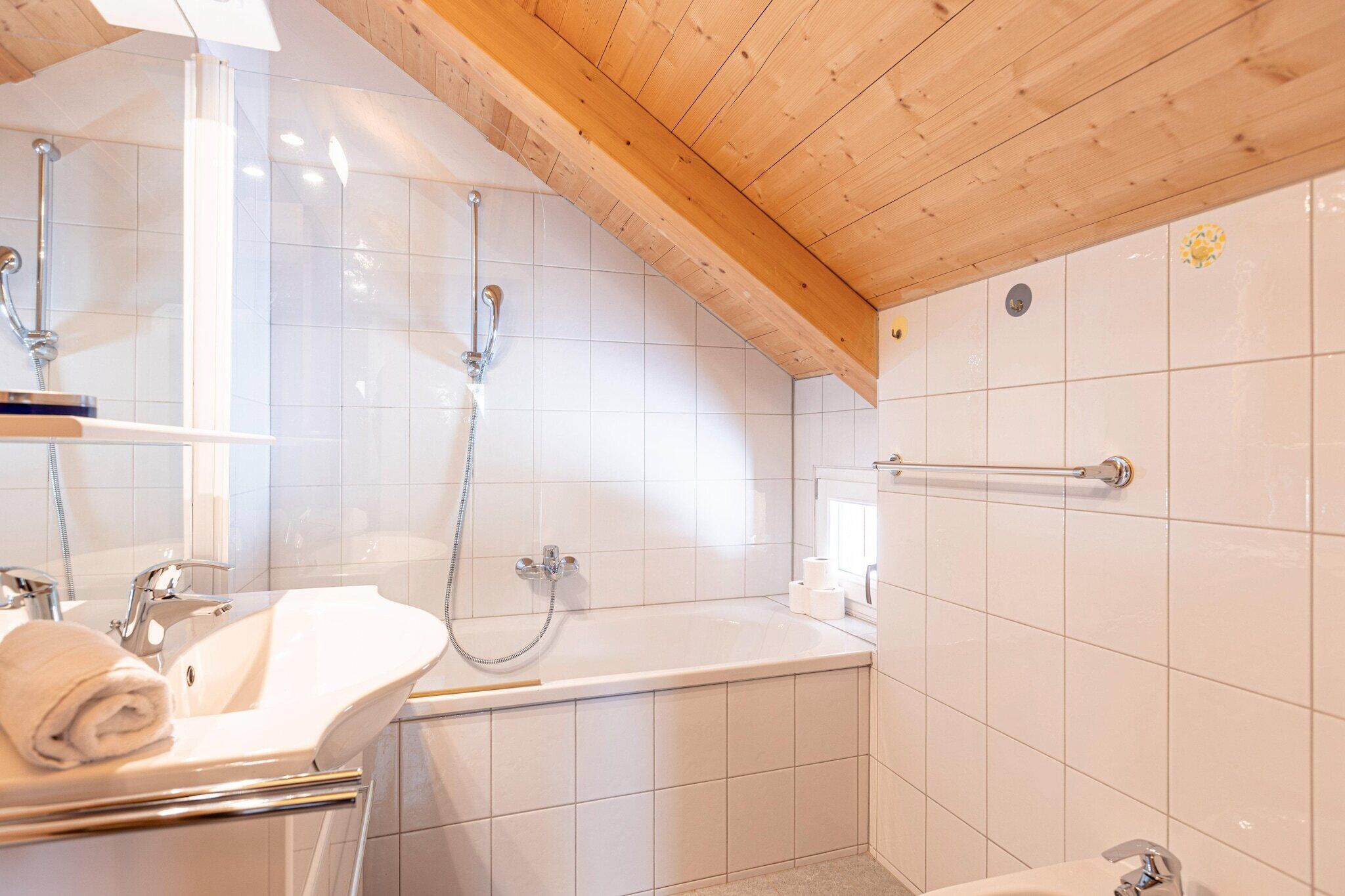 Une salle de bain moderne avec un plafond en bois, une baignoire, un lavabo et une douche.