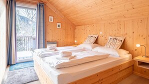 A wooden cabin bedroom with two beds, a window with curtains, and a nightstand with a lamp. - Attractive chalet with sauna (Stadl an der mur)