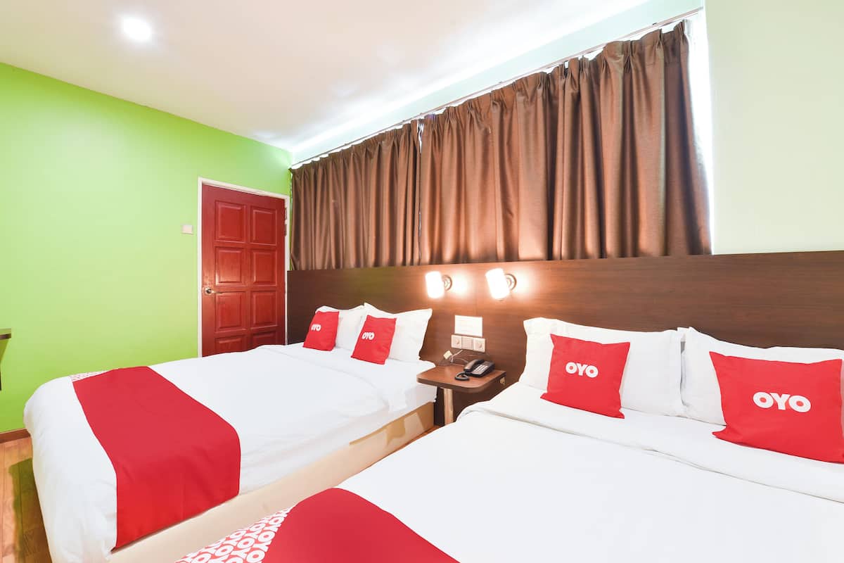 A hotel room with two beds, a wooden headboard, a telephone, and a red door.