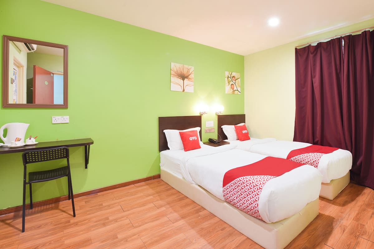 A hotel room with two beds, a desk, a chair, and a mirror.