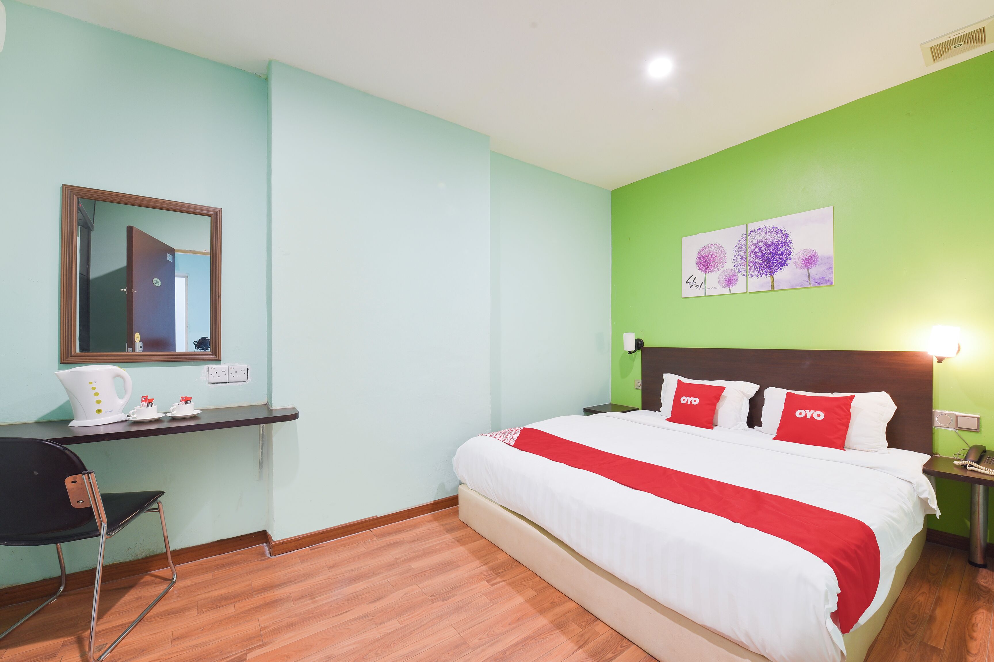 Una habitación de hotel con una cama, un escritorio, una silla y un cuadro en la pared.