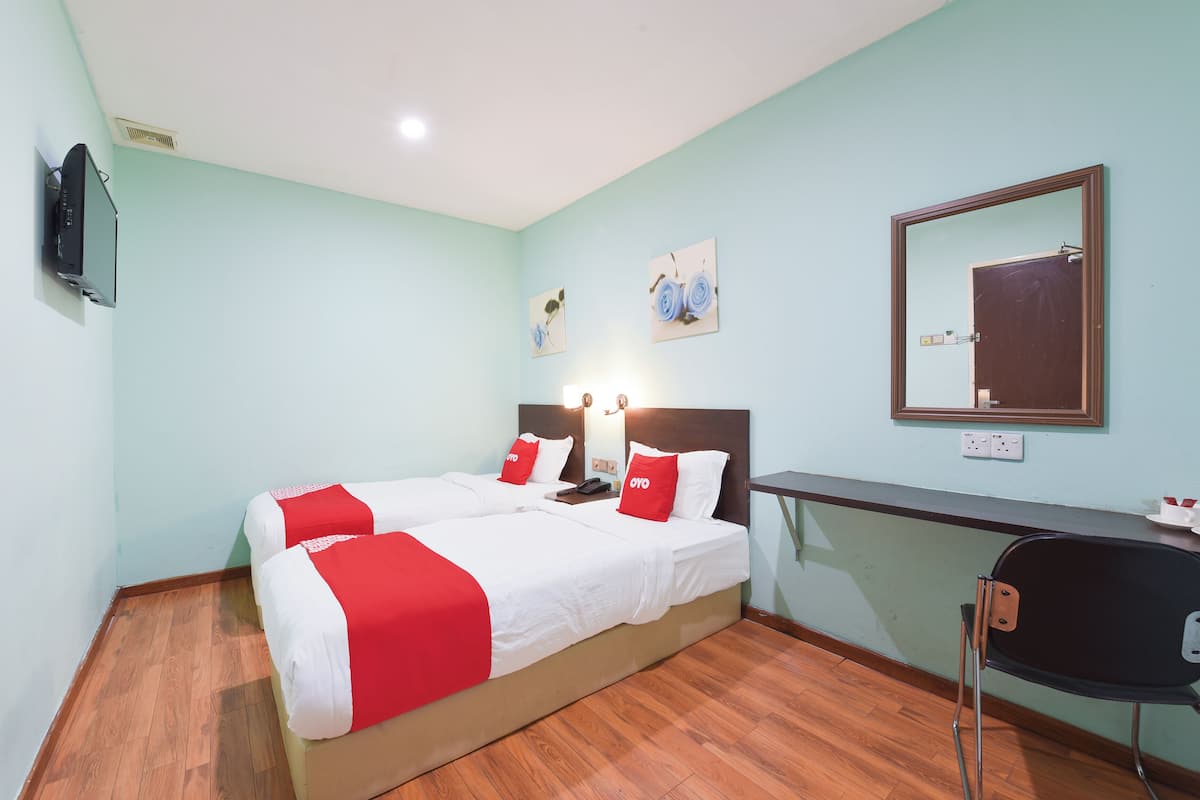 A hotel room with two beds, a desk, a chair, a TV, and artwork on the walls.