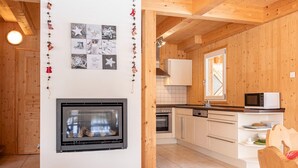 Et moderne køkken med trævægge, en indbygget ovn, mikroovn og et spiseområde med et træbord og stole.
