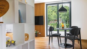 A modern interior with a dining area, large windows, and a wooden accent wall. - Vila Nina Bohinj (Bohinj)