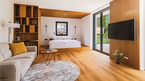 A modern living room with a sofa, a coffee table, a bed with a window, and a TV mounted on the wall. - Vila Nina Bohinj (Bohinj)