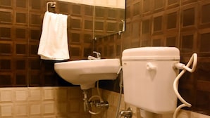 Un baño con inodoro, lavamanos y una toalla colgada en la pared.