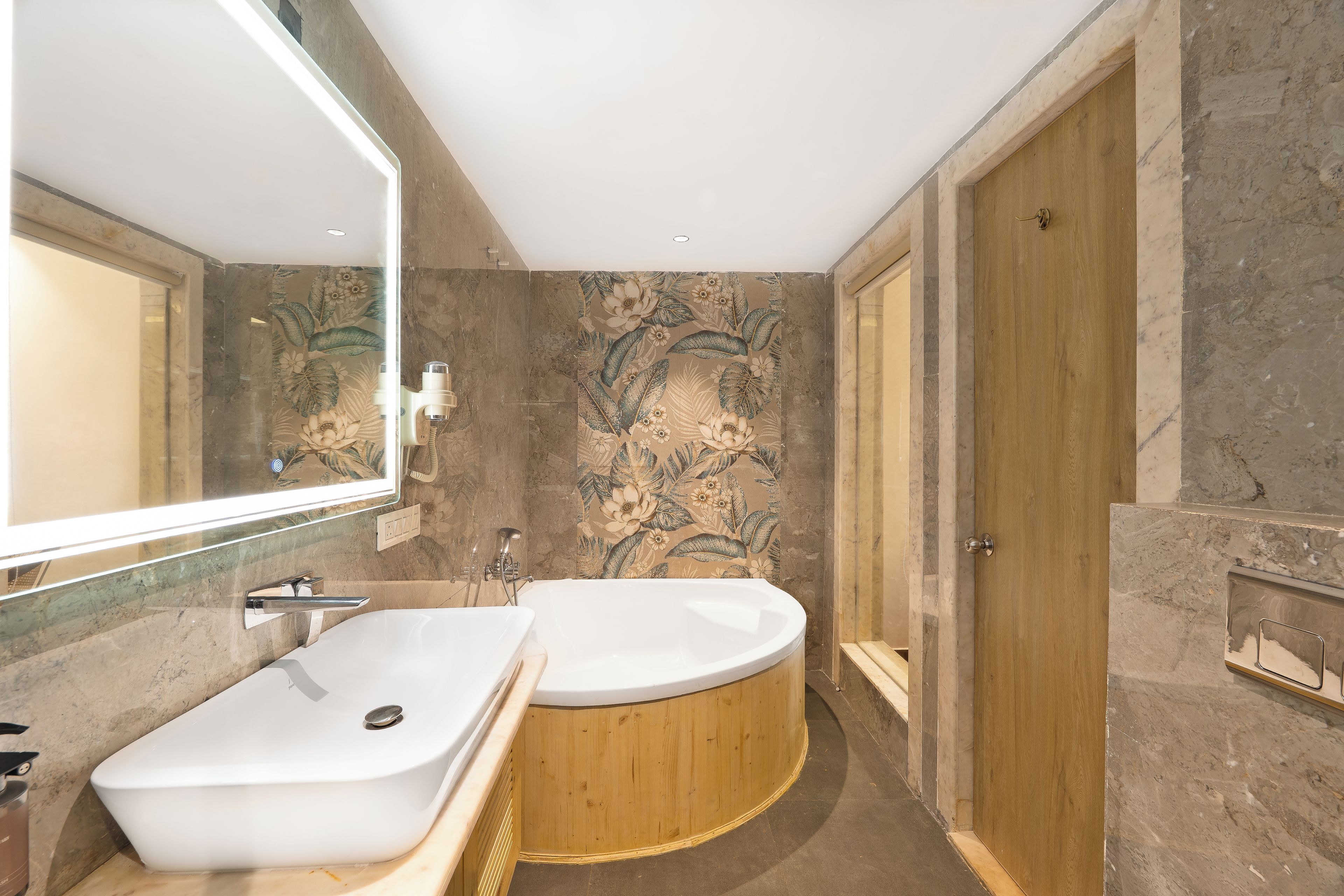 A modern bathroom with a freestanding bathtub, a large mirror, and a wooden door.