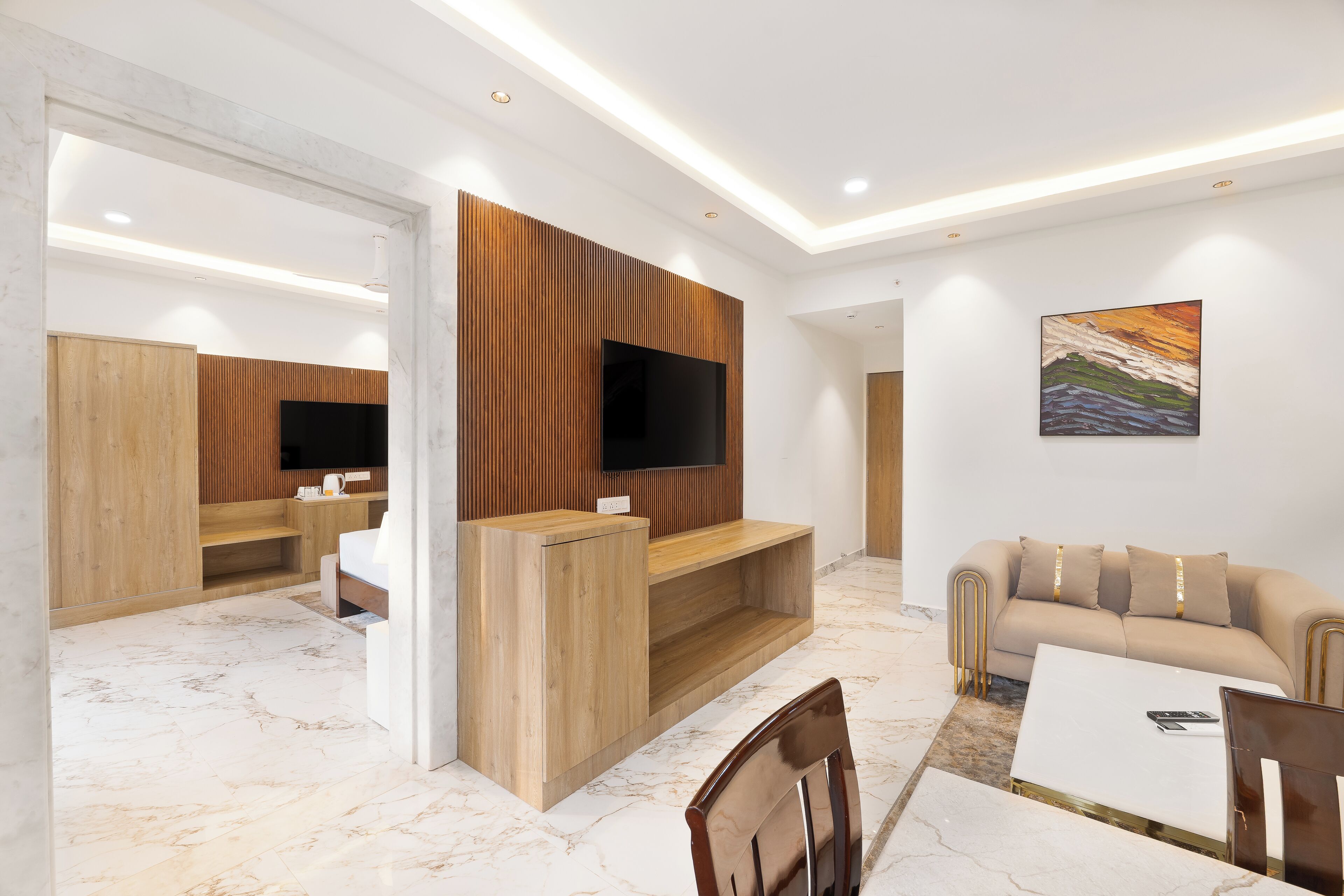Una sala de estar moderna con un mueble de entretenimiento de madera, un televisor de pantalla plana, un sofá color beige y un piso de mármol.