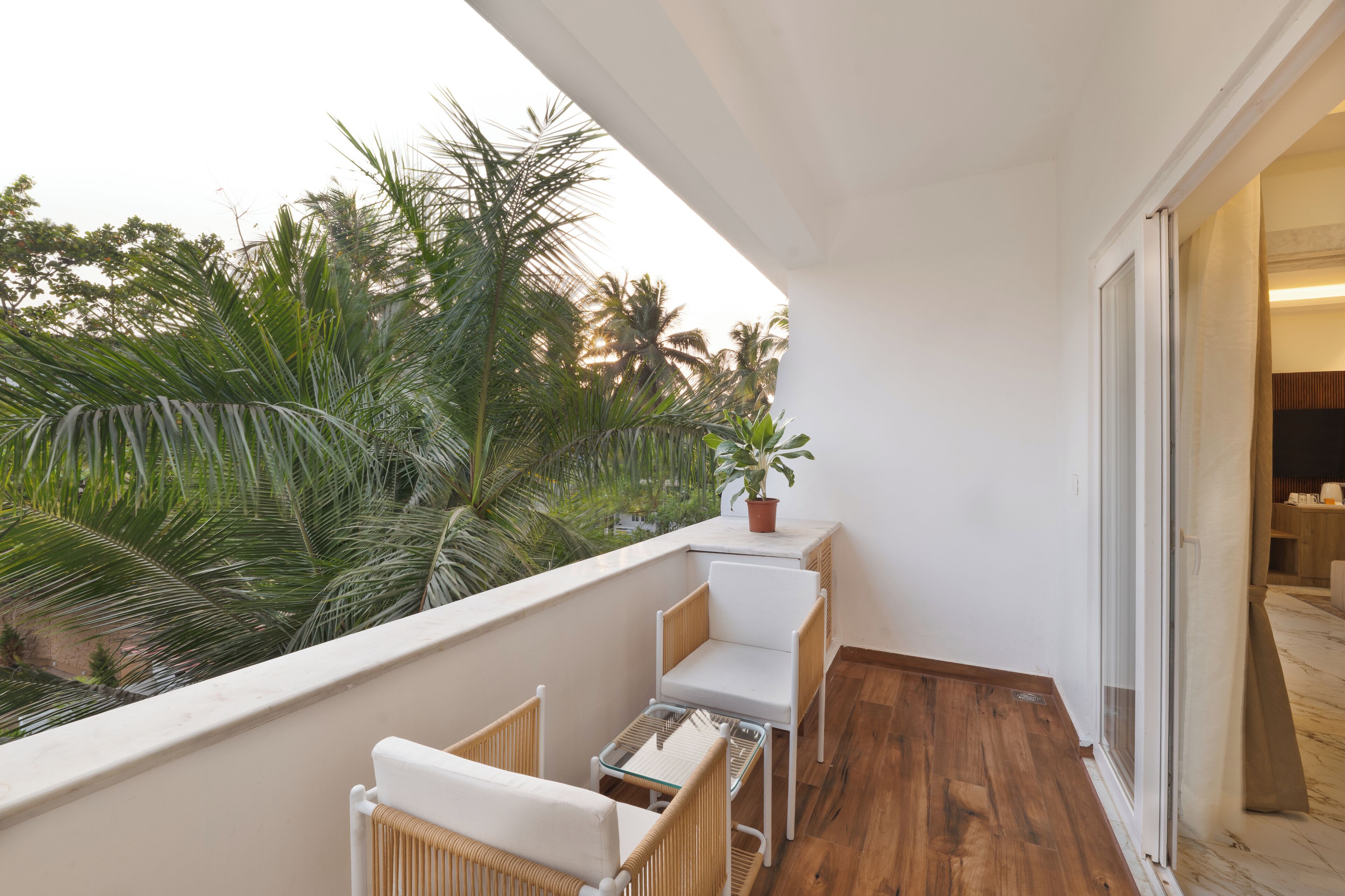 A balcony with wicker furniture, a small table, and a potted plant.