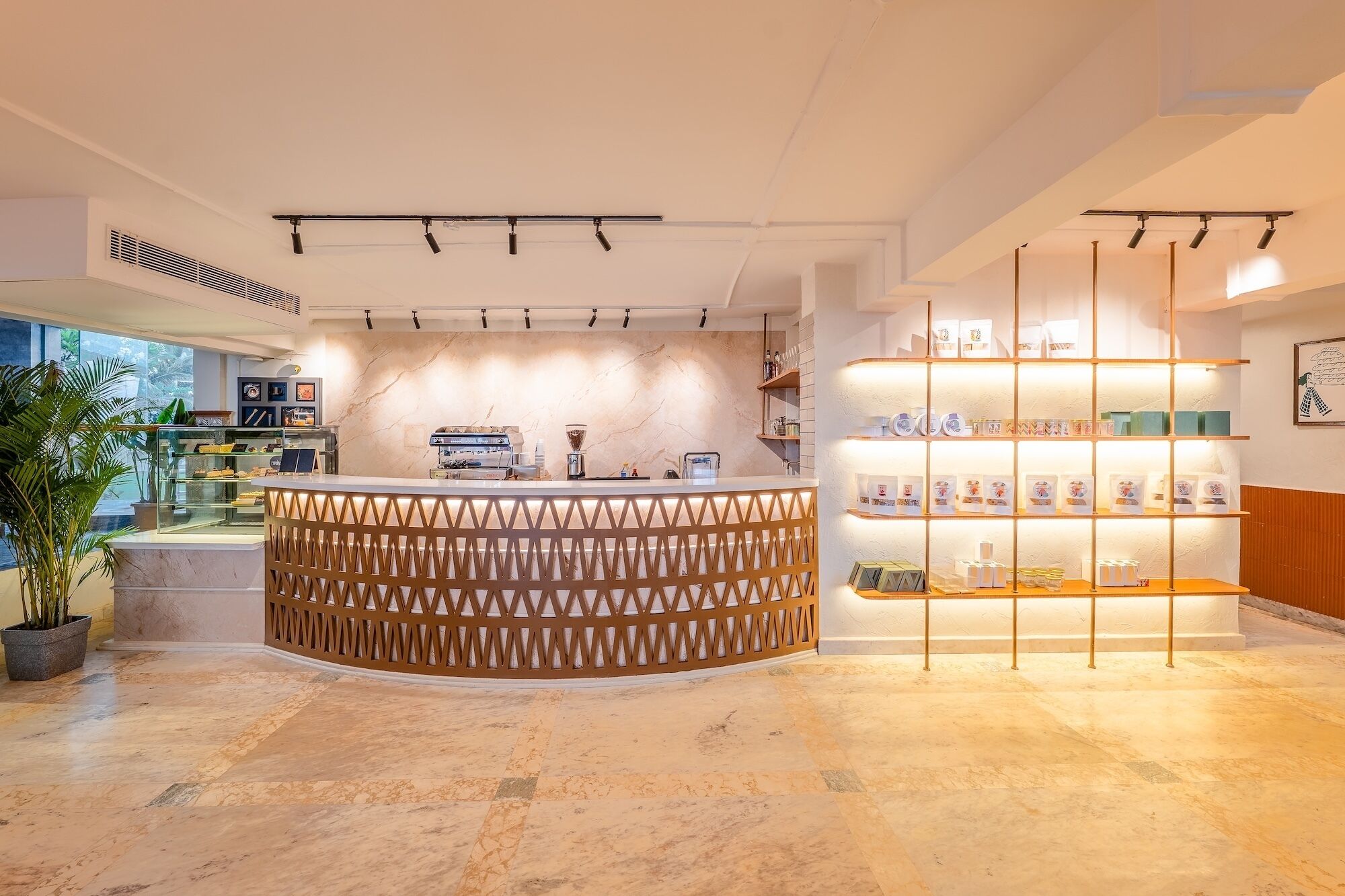 A modern reception area with a curved counter, a coffee machine, and a display of items on shelves.