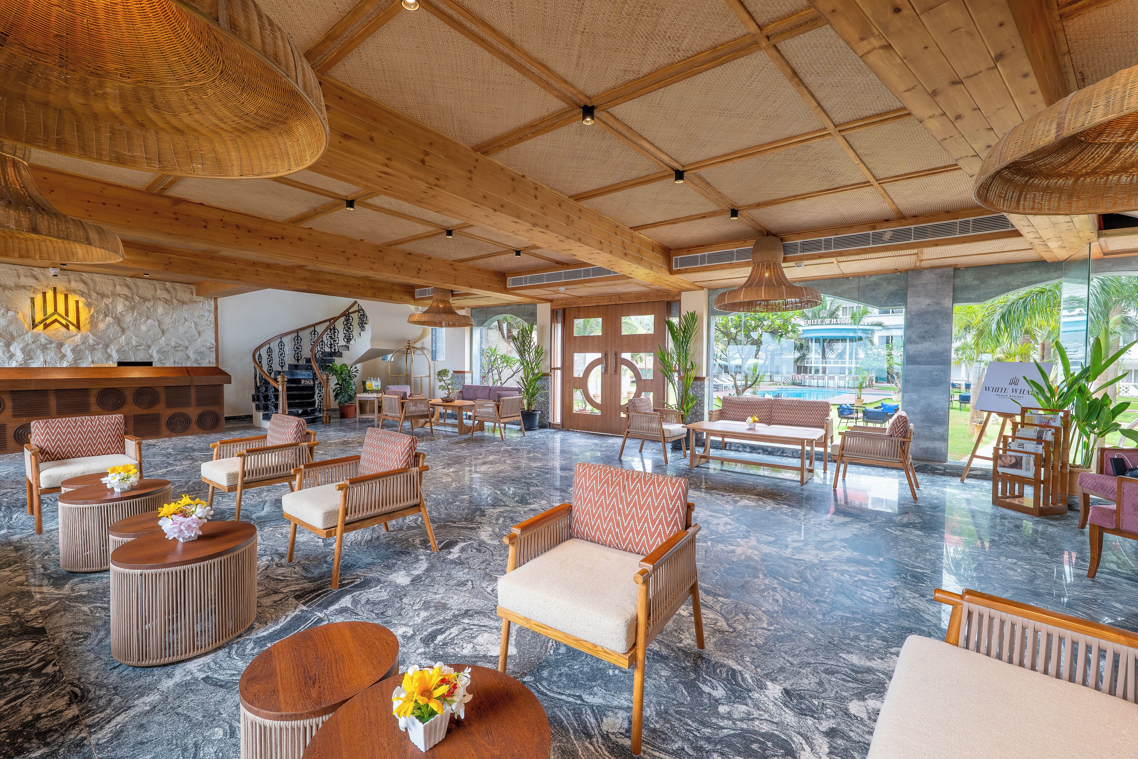 Een ruime lobby met houten meubels, een receptiebalie en grote ramen met uitzicht op het omliggende landschap.