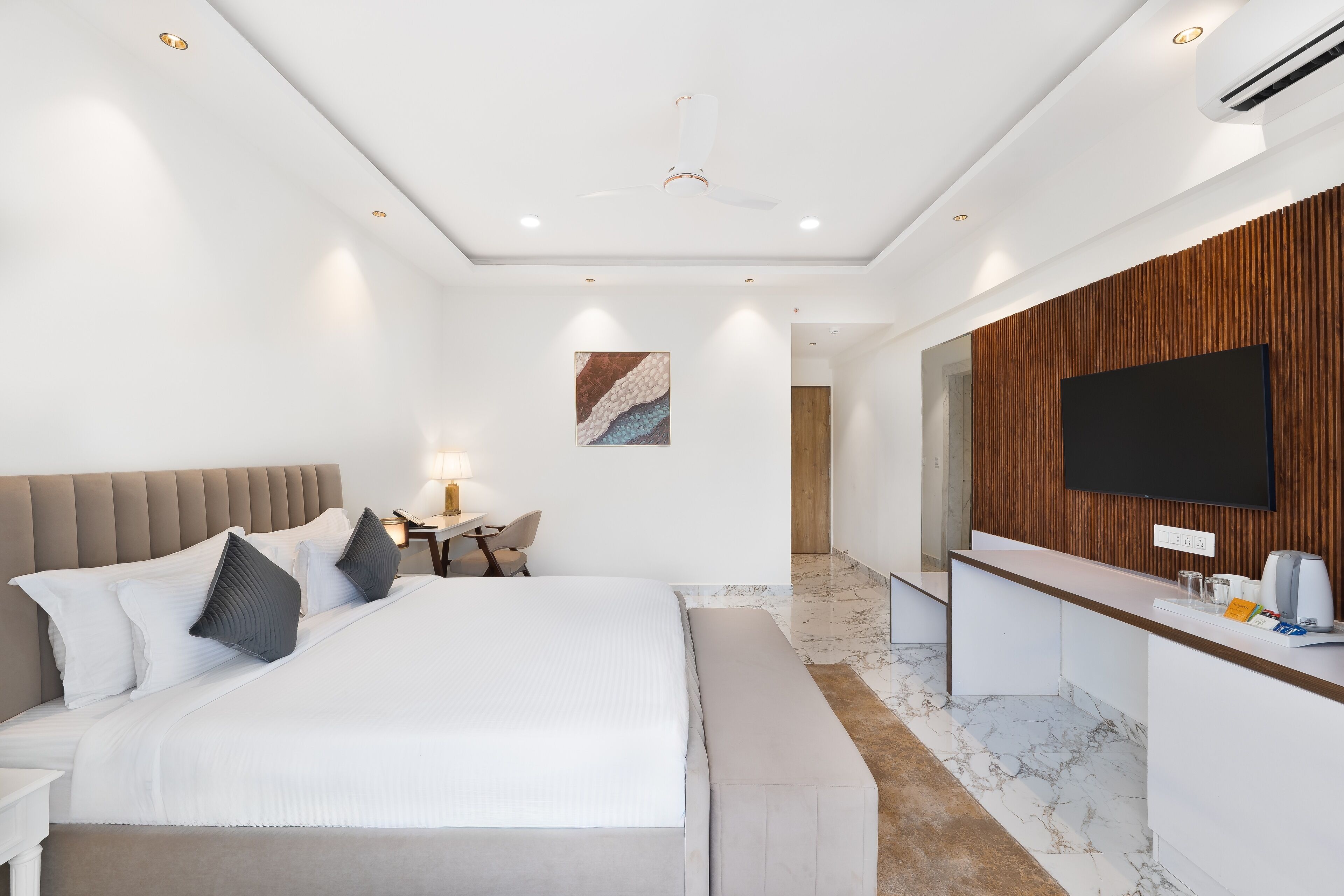 Une chambre d’hôtel moderne dotée d’un grand lit, d’un bureau, d’une télévision à écran plat et d’un mur décoratif en bois.