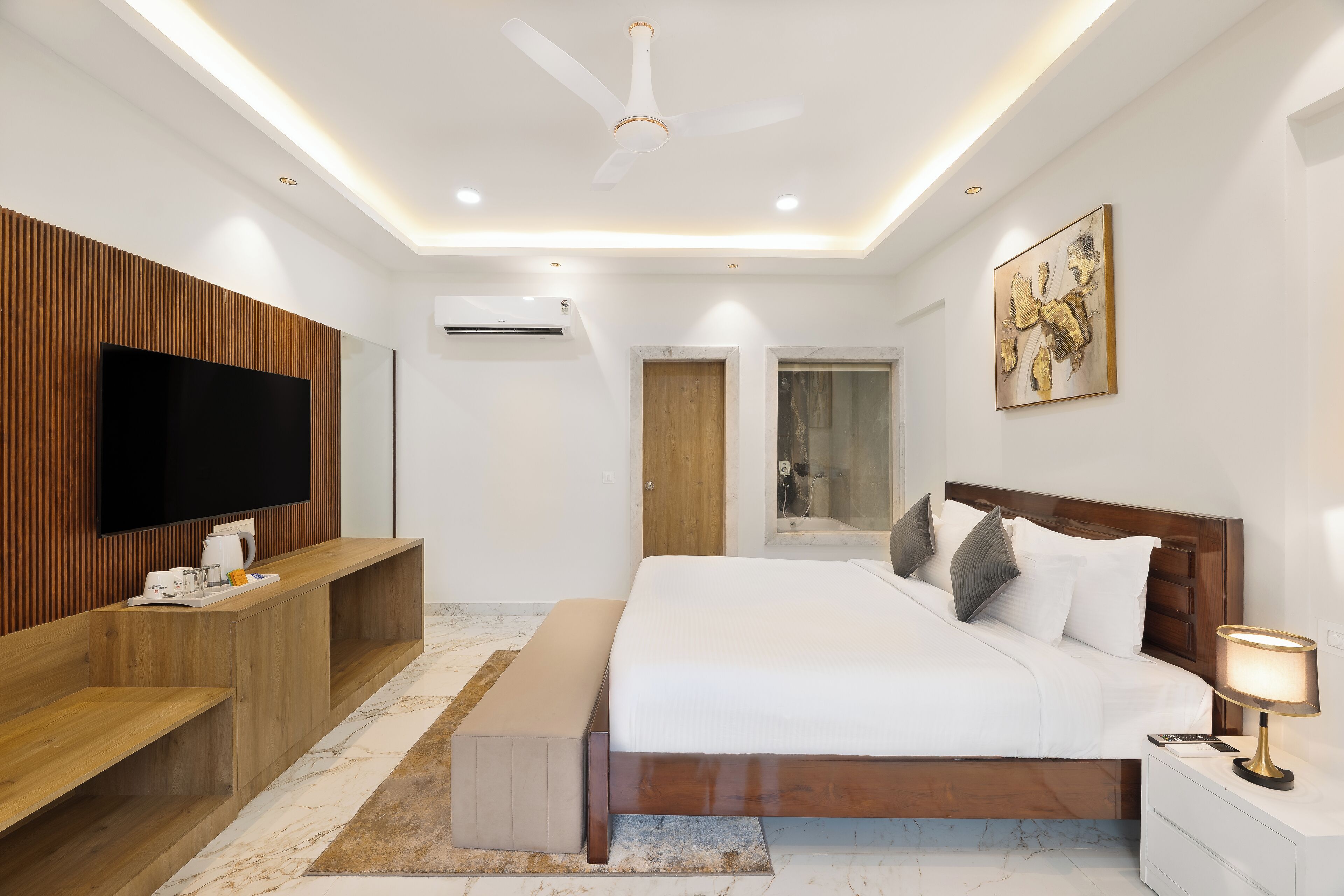 Un dormitorio moderno con una cama grande, paneles de madera, un televisor de pantalla plana y un ventilador de techo.