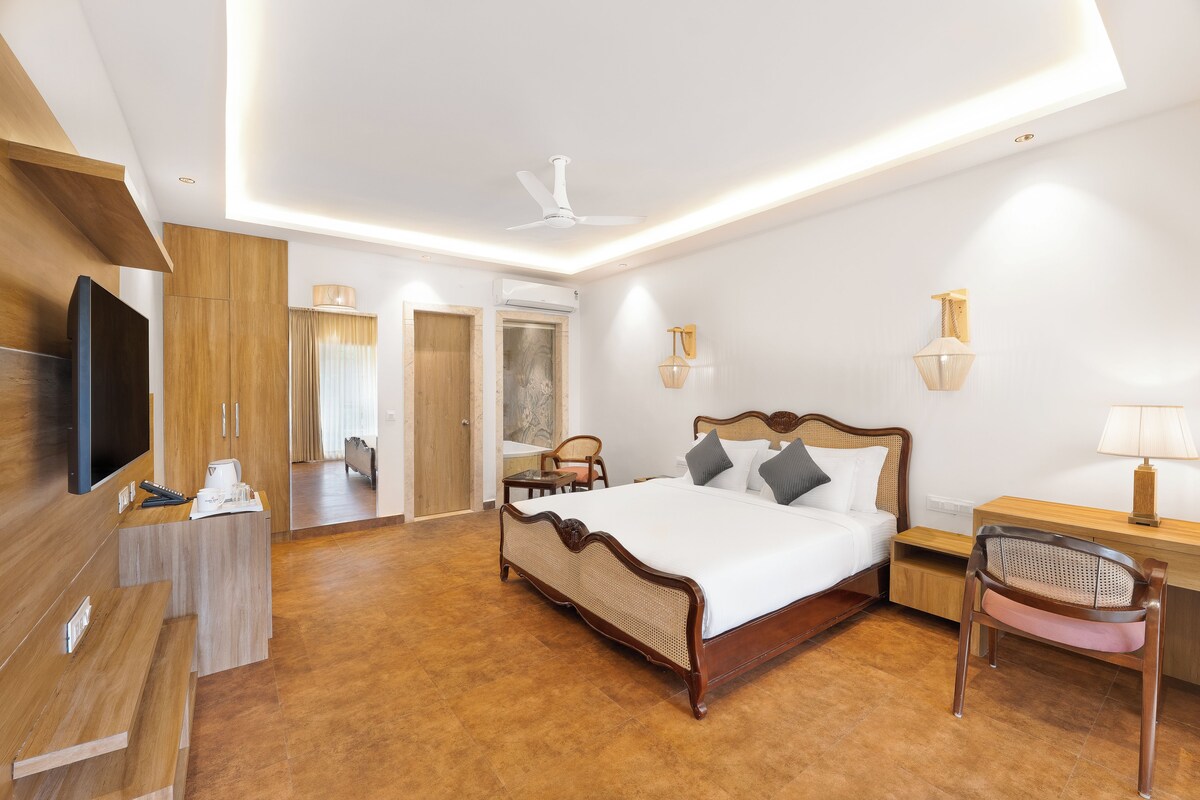 Een moderne hotelkamer met een houten bed, een bureau, een stoel, een televisie en een plafondventilator.