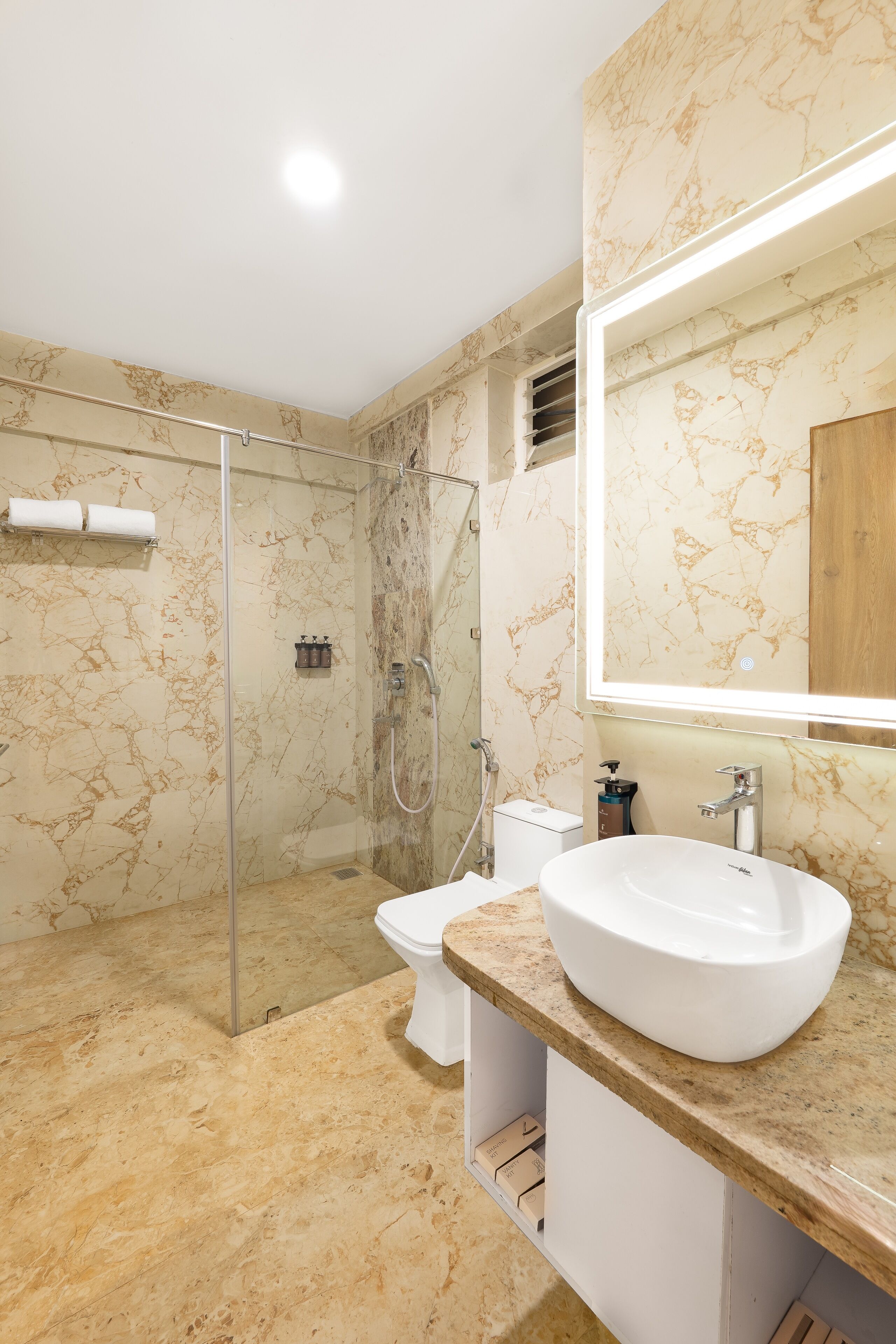 A bathroom with a glass-enclosed shower, a white toilet, and a large sink with a marble countertop.