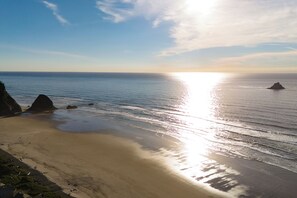 Ein Strand mit blauem Himmel, ruhigem Wasser und Felsen.