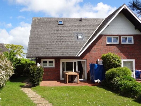 A two-story house with a brick facade, a tiled roof, and a small attached garage.