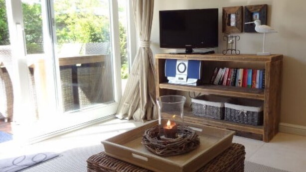 A room with a television, bookshelf, and a candle on a tray. - Holiday Home 'Sylthus-Haithabu' with Private Terrace, Private Garden and Wi-Fi (Wenningstedt)