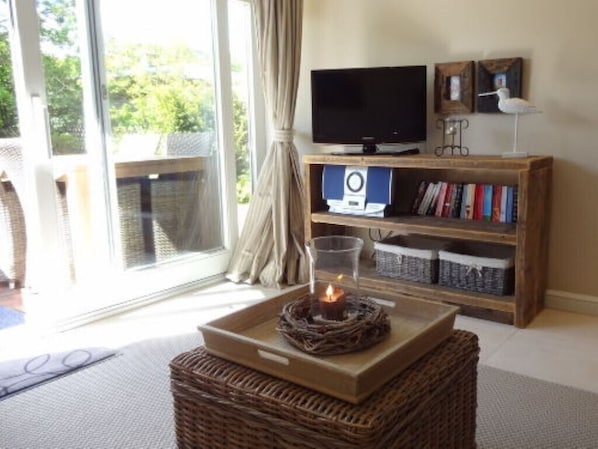 A room with a television, bookshelf, and a candle on a tray.