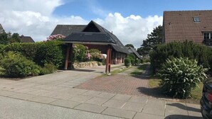 A residential area with a paved driveway leading to a house with a sloped roof and a covered porch. - Holiday Home 'Meerchenhaus' with Private Terrace, Garden, and Wi-Fi (Wenningstedt)