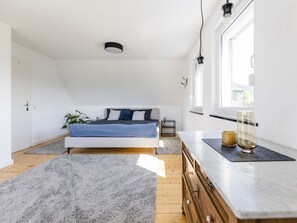 Un dormitorio con cama, mesita de noche y ventana.