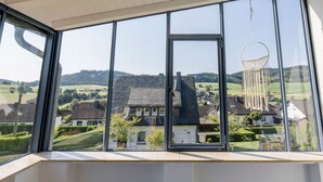 Una habitación con ventanas amplias que ofrecen vistas a una zona residencial con casas y colinas.