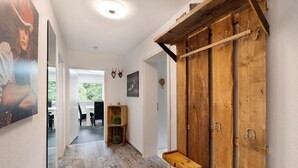 A hallway with wooden beams, a coat rack, and a small shelf. - Apartment 'Villa Eichwald' with Shared Garden, Balcony and Wi-Fi (Freudenstadt)