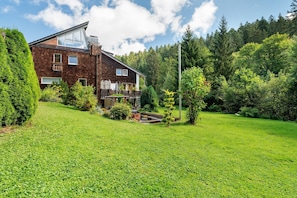 A two-story house with a sloped roof, a visible attic, and a large window on the upper floor. - Apartment 'Villa Eichwald' with Shared Garden, Balcony and Wi-Fi (Freudenstadt)