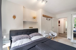 A modern bedroom with a bed, bedside tables, a chair, and a small desk. - Apartment 'Villa Eichwald' with Shared Garden, Balcony and Wi-Fi (Freudenstadt)
