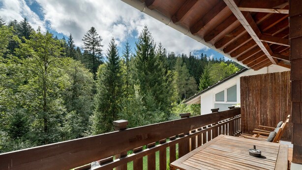 A wooden deck with a table and chairs, overlooking a forested area. - Apartment 'Villa Eichwald' with Shared Garden, Balcony and Wi-Fi (Freudenstadt)