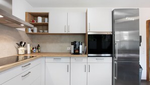 A modern kitchen with white cabinets, a stainless steel refrigerator, and a coffee maker on the counter. - Apartment 'Design Und Entspannug' with Private Terrace, Private Garden and Wi-Fi (Kandern)