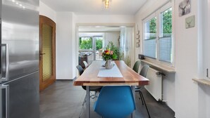 A modern kitchen with a wooden table, chairs, and a refrigerator. - Apartment 'Design Und Entspannug' with Private Terrace, Private Garden and Wi-Fi (Kandern)