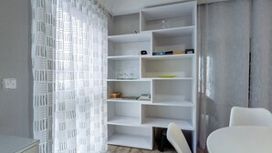 A modern room with a white built-in bookshelf, a white chair, and a desk. - Apartment 'Haus Unterm Hohenstoffel' with Private Terrace and Wi-Fi (Hilzingen)
