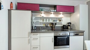 A modern kitchen with white cabinets, a stainless steel stove, and a coffee maker.