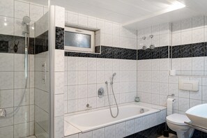 Un baño moderno con ducha, bañera, inodoro y lavabo.