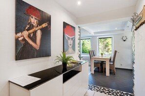 Un interior moderno con una zona de comedor, una encimera negra y obras de arte en la pared.