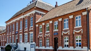 A red brick building with white trim, multiple windows, and a tiled roof.