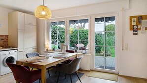A modern kitchen with a dining area, large windows, and a laundry machine.